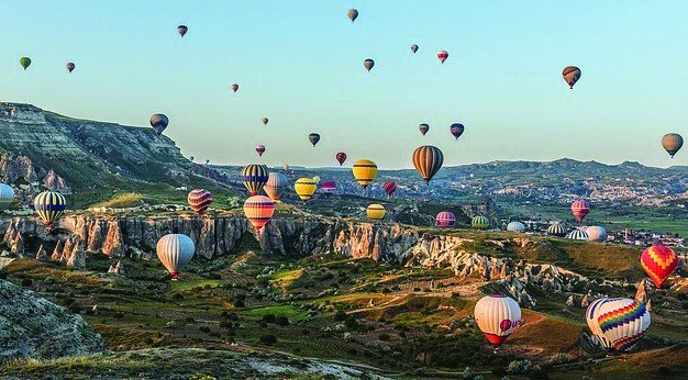 Panoramic view of balloons over rock formations in Cappadocia.